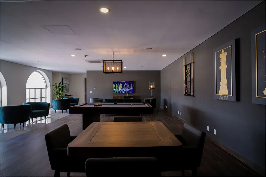 Salón con mesa de billar, mesa de juego y muebles oscuros