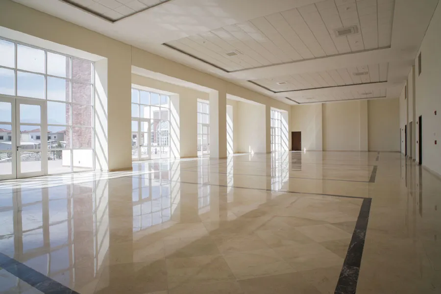 Salón de eventos amplio con piso de mármol y ventanales