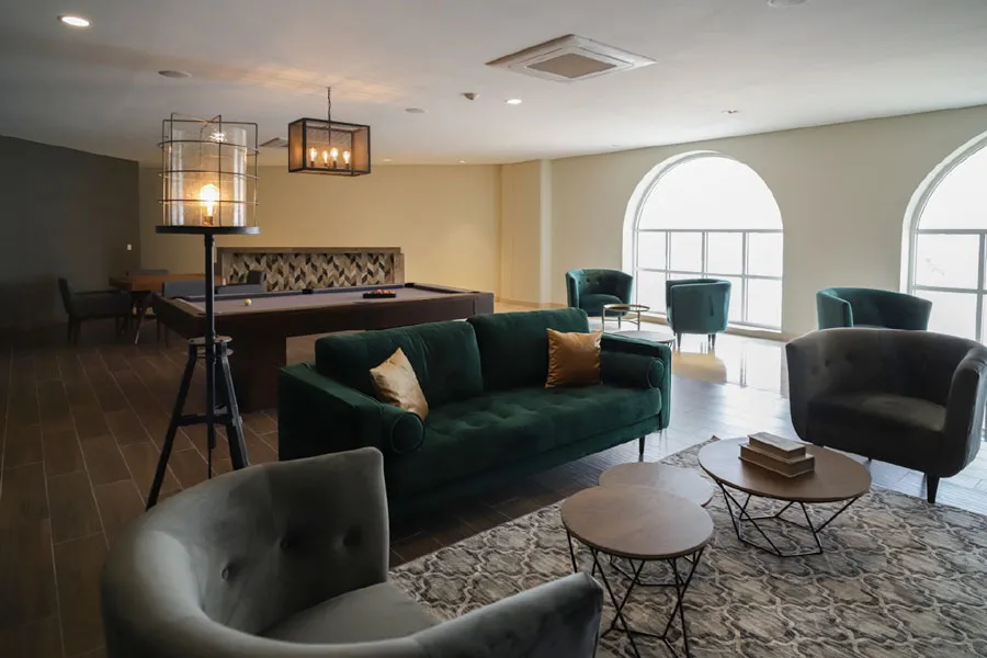 Sala de juegos con mesa de billar y sillones verdes