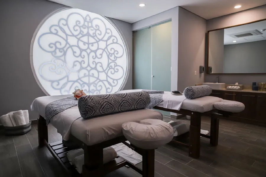 Cabina de spa con camilla de masaje y una ventana circular tallada