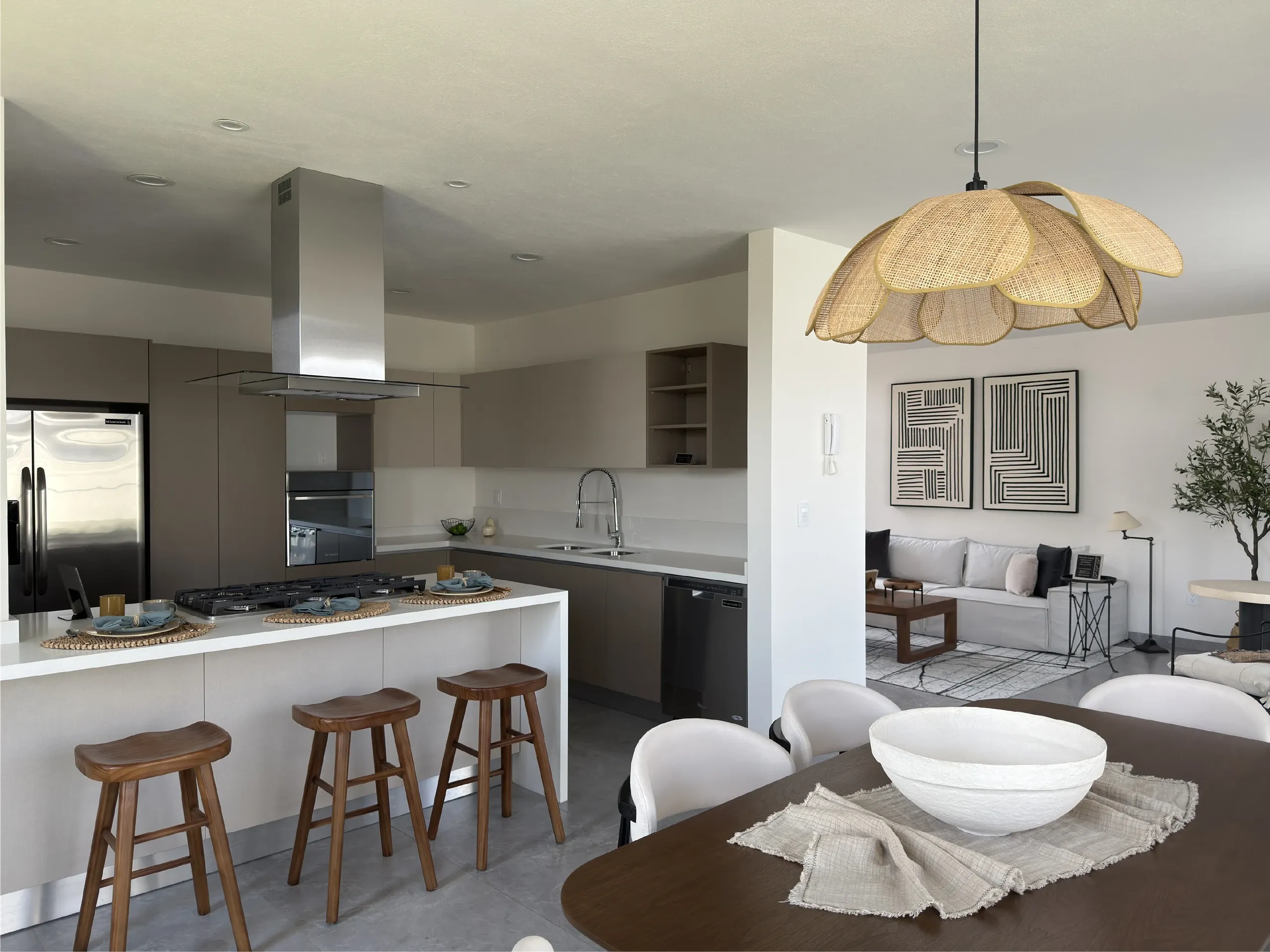 Cocina abierta con barra, taburetes y comedor con lámpara de ratán